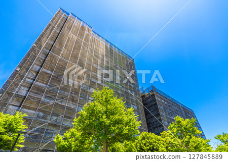 Yokohama cityscape in Japan. Apartment building repairs and inspections, scaffolding and protective nets. Satellite antennas outside the nets... 127845889