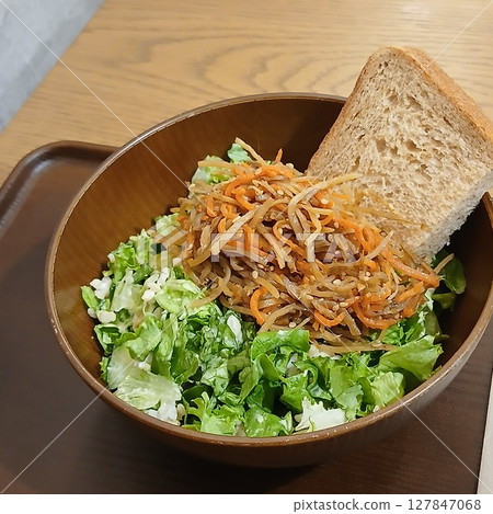 Golden burdock and crunchy salad bowl topped with brown rice bread 127847068