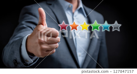 Positive e commerce feedback concept with businessman showing thumbs up and colorful star rating on dark background for success Positive e commerce feedback concept with businessman showing thumbs up and colorful star rating on dark background for success 127847157