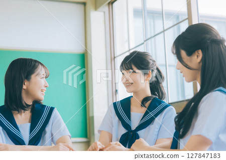 三個高中女生在教室裡聊天 127847183
