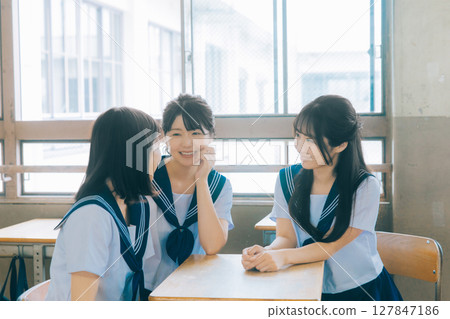 Three high school girls chatting in the classroom Three high school girls chatting in the classroom 127847186