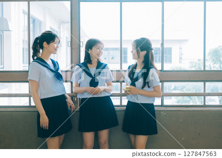 Three high school girls chatting in the classroom Three high school girls chatting in the classroom 127847563