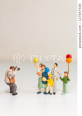 Miniature Family Posing for Photographer with Balloons 127847589