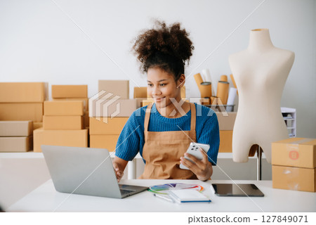 Young woman holding a smartphone, tablet showing payment success and credit card with yellow parcel box as online shopping concept 127849071