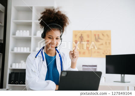 female doctor sitting on work desk Medical online, e health concept. Doctor using laptop for work, video call video chat with colleagues. female doctor sitting on work desk Medical online, e health concept. Doctor using laptop for work, video call video chat with colleagues. 127849104