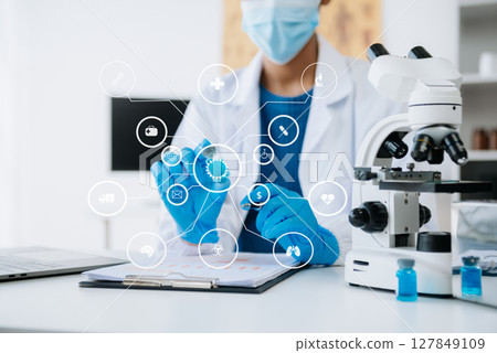Young scientists conducting research investigations in a medical laboratory, a researcher in the foreground is using a microscope in laboratory for medicine. Young scientists conducting research investigations in a medical laboratory, a researcher in the foreground is using a microscope in laboratory for medicine. 127849109