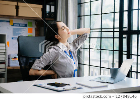 Asian woman feeling migraine head strain.Overworked businesswoman financier while working on laptop and tablet Asian woman feeling migraine head strain.Overworked businesswoman financier while working on laptop and tablet 127849146