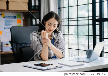Asian woman feeling migraine head strain.Overworked businesswoman financier while working on laptop and tablet 127849147