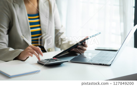 Businessman hands working with finances about cost and calculator and laptop with tablet, smartphone at office Businessman hands working with finances about cost and calculator and laptop with tablet, smartphone at office 127849200