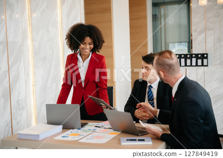 Group of young business people discussing business plan at modern startup in creative business discussing work modern office building Group of young business people discussing business plan at modern startup in creative business discussing work modern office building 127849419