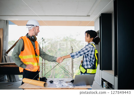 Construction team shake hands greeting start new project plan behind yellow helmet in office center to consults about their building project. 127849443