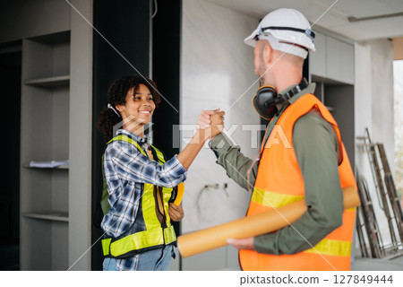 Construction team shake hands greeting start new project plan behind yellow helmet in office center to consults about their building project. Construction team shake hands greeting start new project plan behind yellow helmet in office center to consults about their building project. 127849444