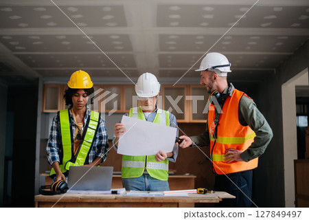 Engineers are discussing data working and laptop or tablet with architectural project at new construction site on big project. 127849497