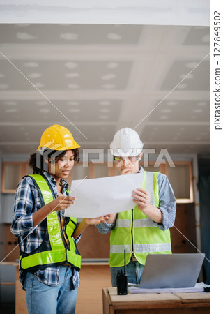 Engineers are discussing data working and laptop or tablet with architectural project at new construction site on big project. 127849502