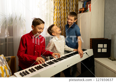 Three boys laughing and playing the piano together 127850637
