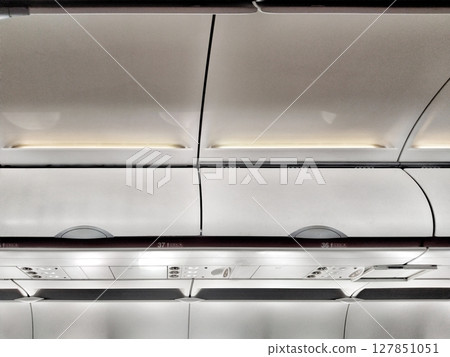 Overhead compartments on an airplane offer storage for carry-on luggage during flight, featuring numbers for seat assignments Overhead compartments on an airplane offer storage for carry-on luggage during flight, featuring numbers for seat assignments 127851051