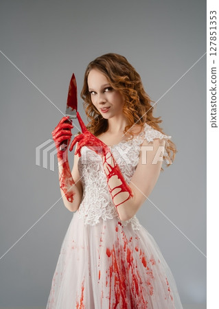 Bride in bloodstained lingerie holds katana with a sinister smile 127851353