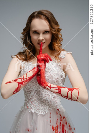 Beautiful bride in white dress with red hands creates a striking contrast 127851356