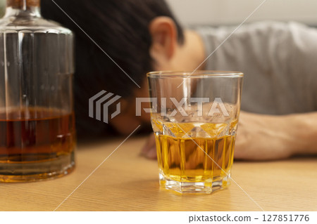 Alcohol addicted man sleeping at the table. Sad depressed male adult having troubles with alcohol. Alcohol addicted man sleeping at the table. Sad depressed male adult having troubles with alcohol. 127851776