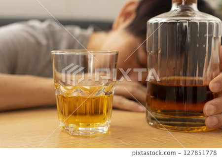 Alcohol addicted man sleeping at the table. Sad depressed male adult having troubles with alcohol. Alcohol addicted man sleeping at the table. Sad depressed male adult having troubles with alcohol. 127851778