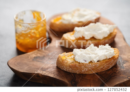 Ciabatta slices with orange marmalade and ricotta on olive board Ciabatta slices with orange marmalade and ricotta on olive board 127852432