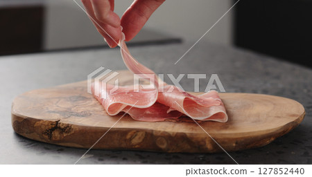 man hand put prosciutto on wood board man hand put prosciutto on wood board 127852440