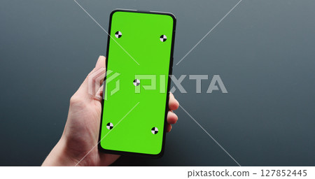 young woman sitting at the black table near window and holding smartphone with vertical green screen young woman sitting at the black table near window and holding smartphone with vertical green screen 127852445