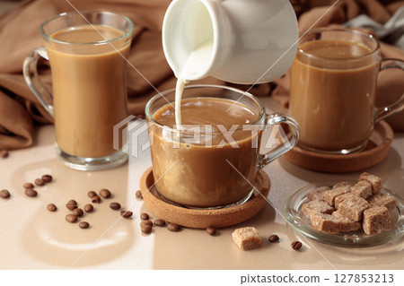 Pouring cream in black coffee. 127853213