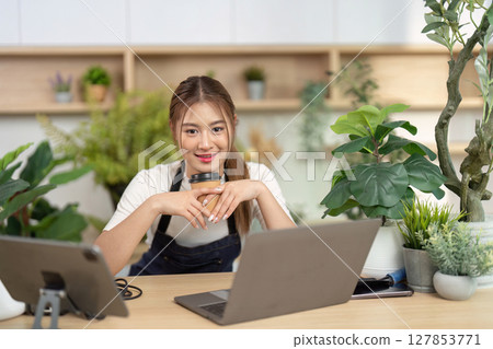 Remote Work and Wellness. Young woman enjoying coffee while working on a laptop. 127853771