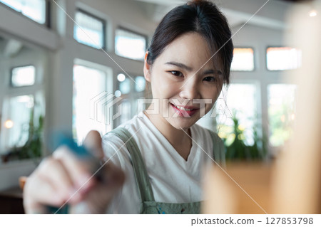 Young Woman Enjoying Creative Hobby Indoors - Smiling Female Engaged in Artistic Activity at Home - Bright and Airy Room with Natural Light - Focus on Leisure and Personal Development Young Woman Enjoying Creative Hobby Indoors - Smiling Female Engaged in Artistic Activity at Home - Bright and Airy Room with Natural Light - Focus on Leisure and Personal Development 127853798