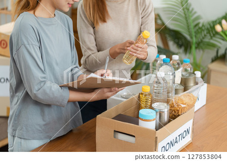 Volunteer Organizing Food Donations in Boxes for Charity - Community Support and Social Responsibility Concept 127853804