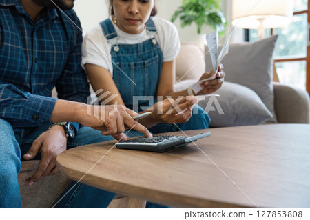 Indian Couple Managing Finances at Home, Paying Bills, and Planning Budget Together in a Modern Living Room 127853808