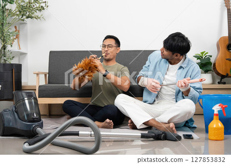 Musical Cleaning Fun. Two friends enjoying a lively cleaning session at home. Musical Cleaning Fun. Two friends enjoying a lively cleaning session at home. 127853832