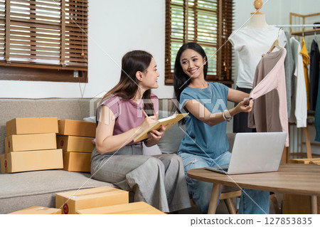 Young Female Entrepreneurs Running an Online E-Business from Home, Discussing Orders and Packing Products, Modern E-Commerce Concept Young Female Entrepreneurs Running an Online E-Business from Home, Discussing Orders and Packing Products, Modern E-Commerce Concept 127853835