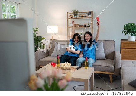 At Home Soccer Fans Sitting on a Couch Watch Football Game on TV, Cheer for Favourtite Sports Team to Win Championship 127853949