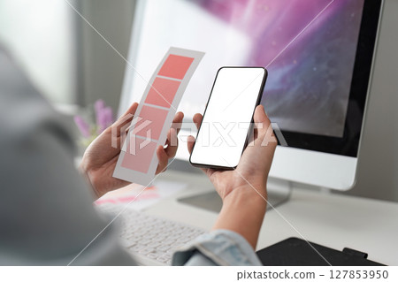 Close-Up of Designer Comparing Color Swatches with Smartphone Mockup, Indoors Concept of digital design and creativity 127853950