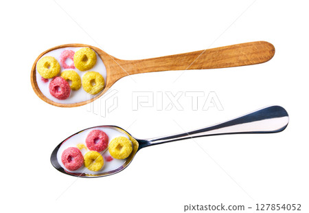 corn rings and strawberry rings with milk in a metal spoon isolated on white background, top view. corn flakes fruity loops colorful hoops. 127854052