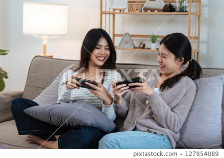 pride month Happy women lesbians lgbt couple spending time together at home in the evening, relaxing, playing game together in the living room. LGBTQ couple concept 127854089