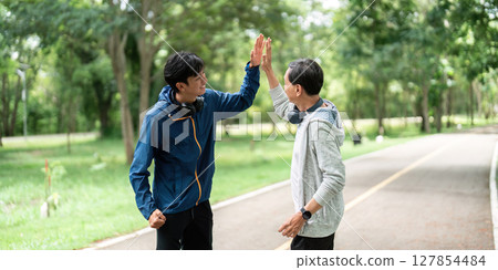 Father and Son Celebrate Wellness. High five after successful workout in the park. Father and Son Celebrate Wellness. High five after successful workout in the park. 127854484