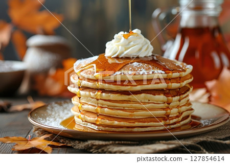 A stack of pancakes with syrup and whipped cream on top 127854614