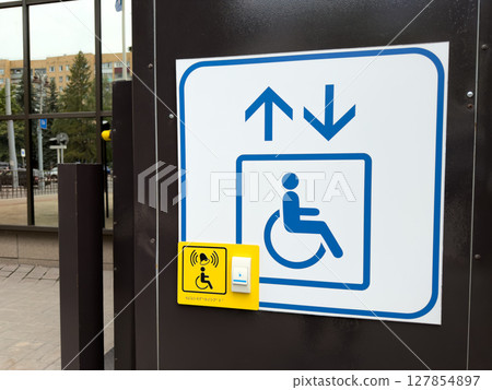 Close up view of accessibility lift call button and sign at a public building entrance, highlighting inclusive infrastructure and wheelchair accessibility in urban environments 127854897