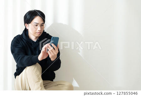 Looking at your smartphone by the wall Looking at your smartphone by the wall 127855046