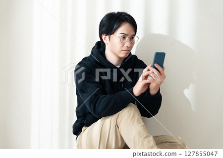 Looking at your smartphone by the wall Looking at your smartphone by the wall 127855047
