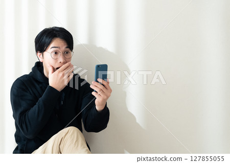 Looking at your smartphone by the wall Looking at your smartphone by the wall 127855055