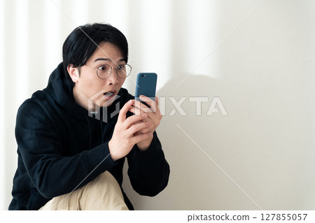 Looking at your smartphone by the wall Looking at your smartphone by the wall 127855057