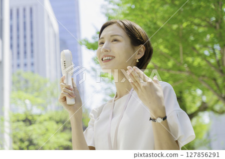 辦公區裡拿著手持風扇的年輕女商人 辦公區裡拿著手持風扇的年輕女商人 127856291