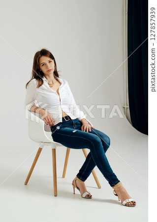 Teenager sitting on a chair in a minimalistic studio setting with natural light Teenager sitting on a chair in a minimalistic studio setting with natural light 127857939