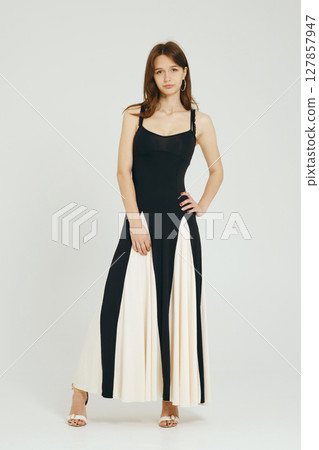 Teenager wearing a modern black and white dress against a plain background in a fashion display 127857947