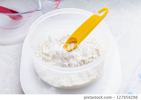 Bread making: Adding dry yeast using a measuring spoon Bread making: Adding dry yeast using a measuring spoon 127858298