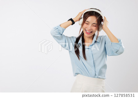 Music in headphones lifts the mood of this smiling young Asian woman, listening as music flows with her lifestyle and joyful emotions. isolated studio white background Music in headphones lifts the mood of this smiling young Asian woman, listening as music flows with her lifestyle and joyful emotions. isolated studio white background 127858531